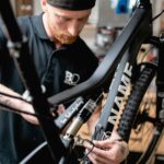 Businessfotografie Portrait eines Unternehmers mit letzten handwerklichen Griffen zum fertigstellen eines hochwertigen Fahrrads von NoName Bikes