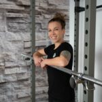 Personal Branding Businessfotografie Portrait einer Frau angelehnt an ein Fitnessgerät