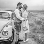 Hochzeitsfoto eines Brautpaares im an einem VW Käfer Küssend