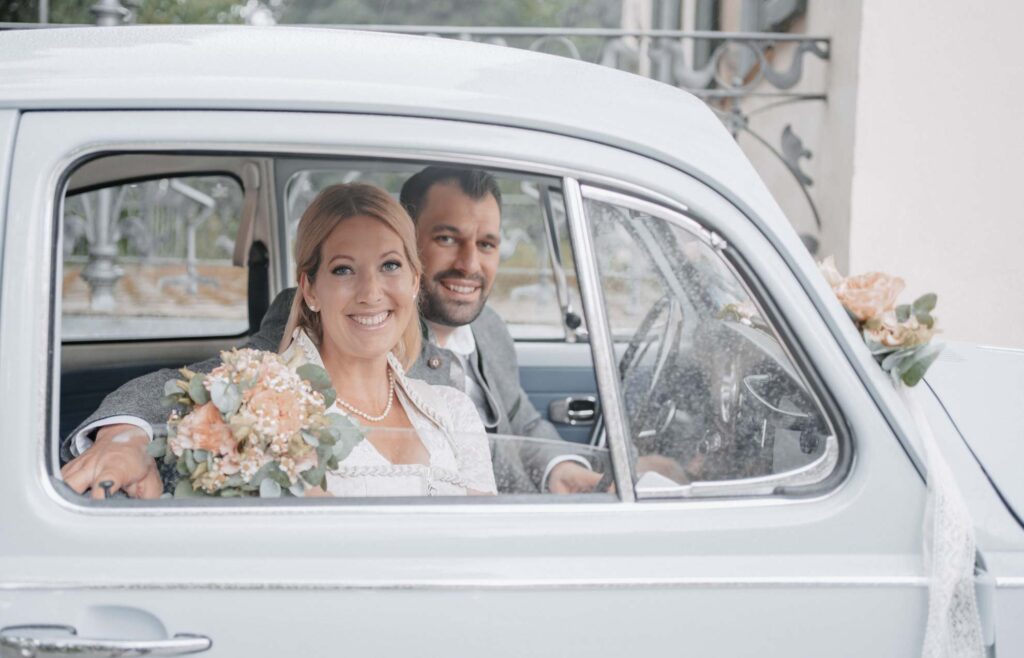 Hochzeitsfoto eines Brautpaares im in einem VW Käfer