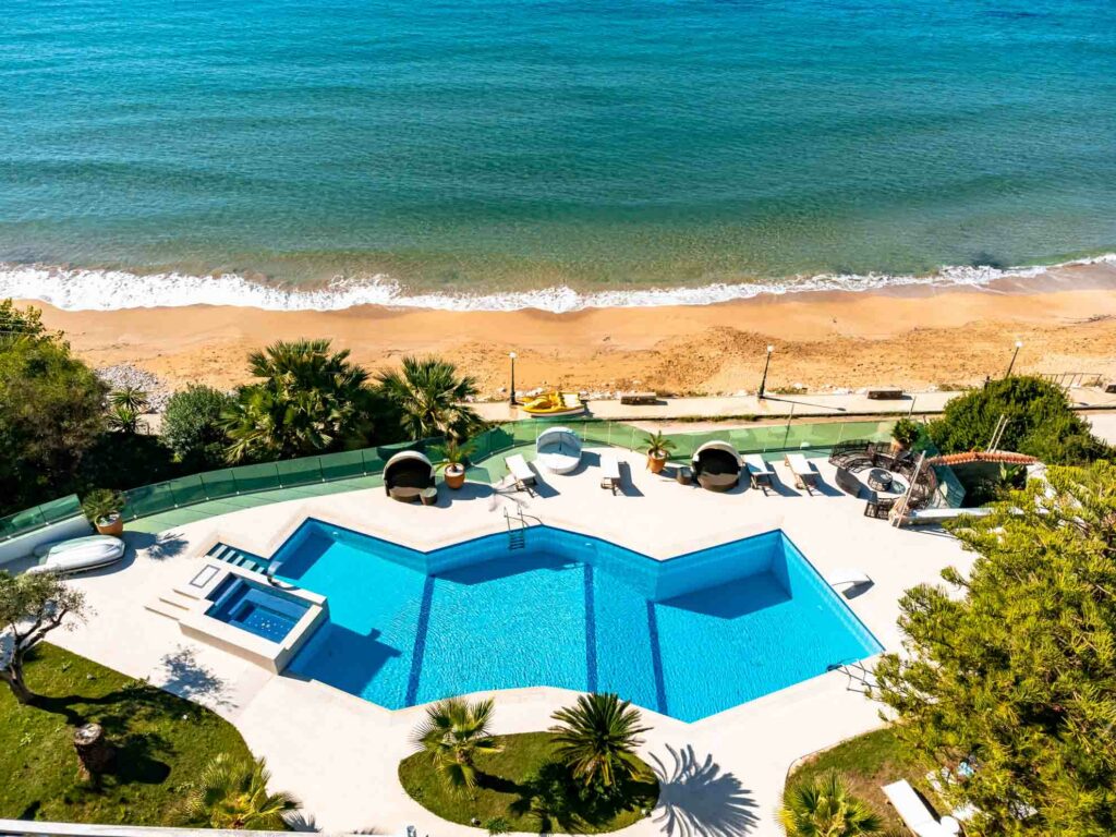 Drohnenaufnahme des Pools direkt vor dem Strand und dem Meer