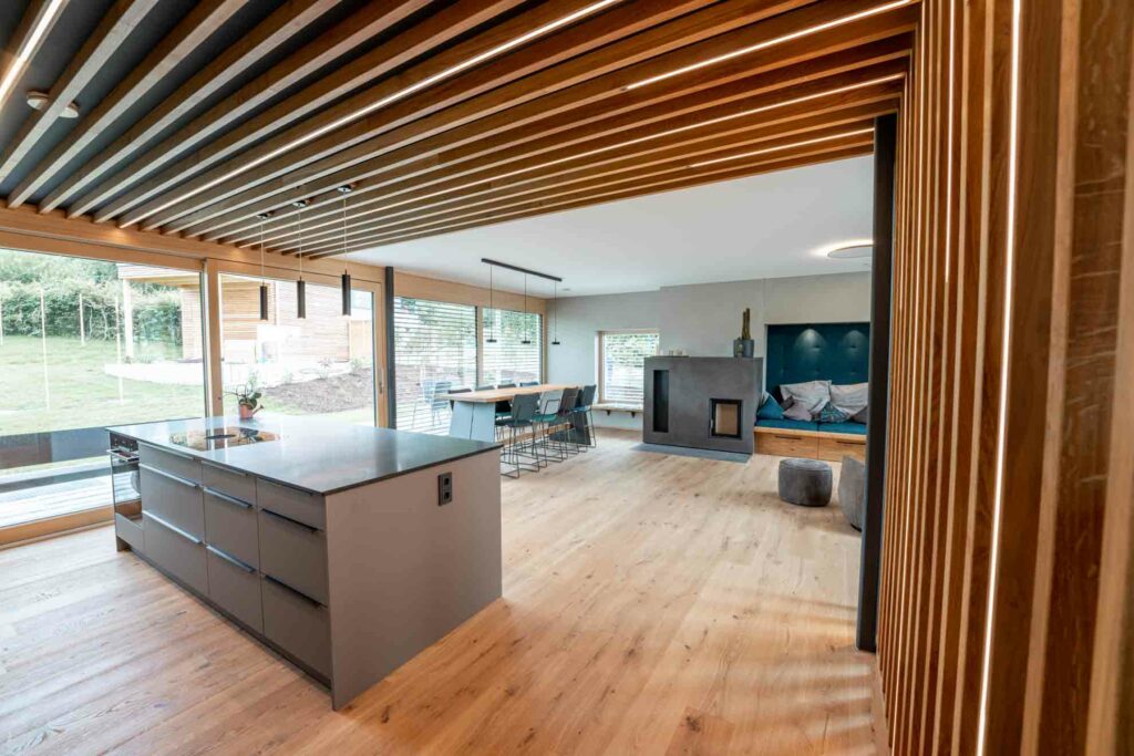Interieurfotografie der Küche mit Blick auf den Wohnraumes mit Esstisch, Holzofen und Sessel