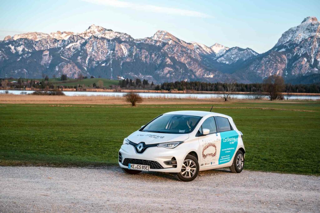 Carsharing E-Auto für E-Mobilität am Hopfensee vor Schloss Neuschwanstein und den Ostallgäuer Bergen