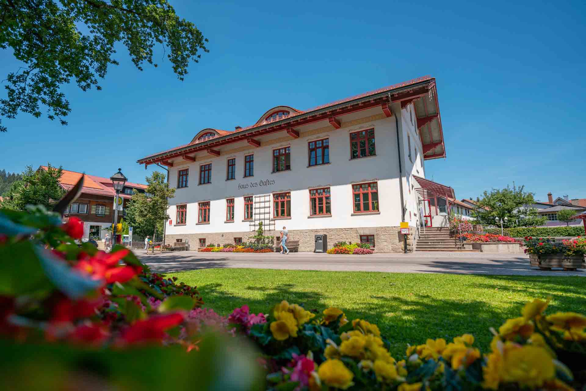 Oberstaufen Tourismus Information Immobilienfoto mit Blumen im Vordergrund